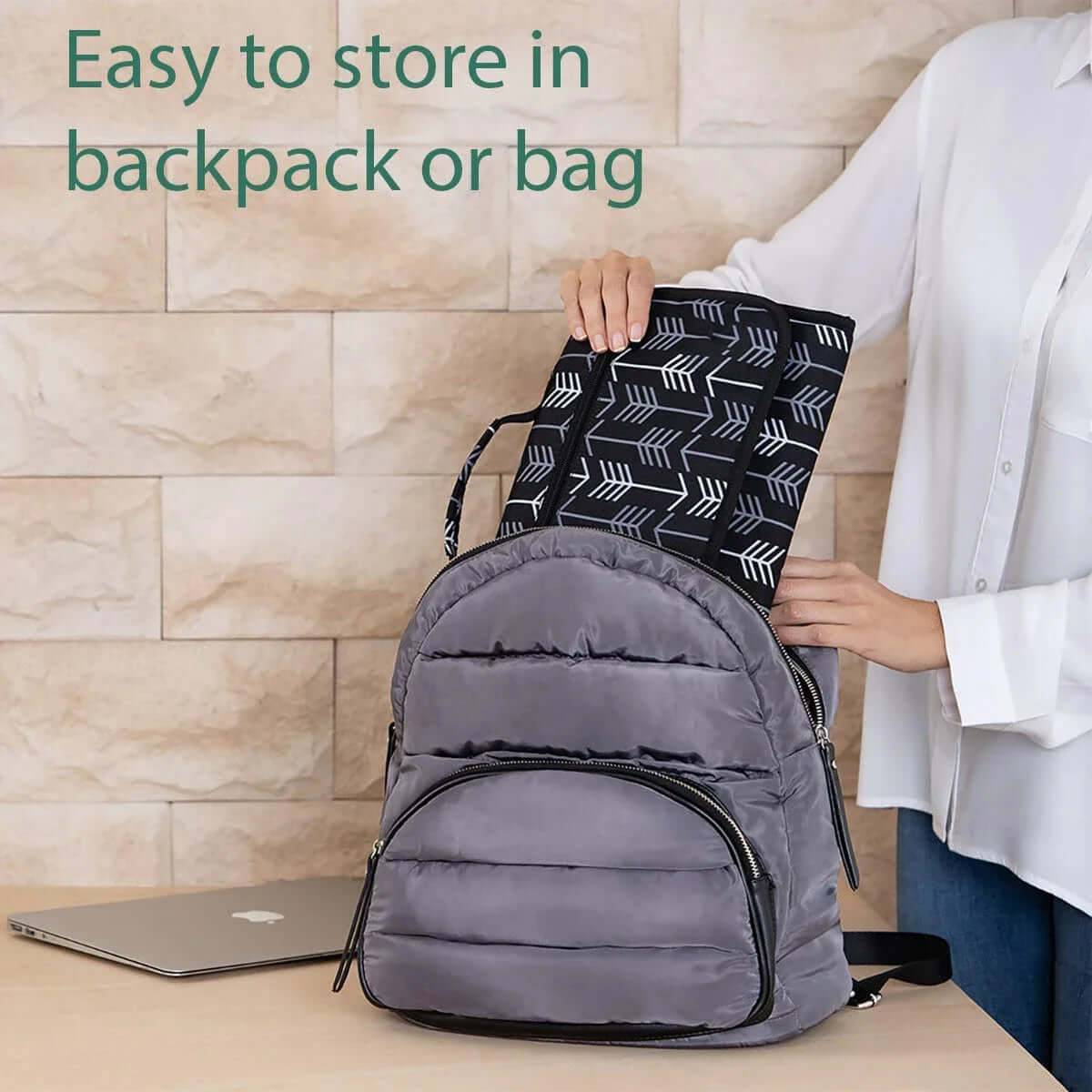 A person placing the portable baby nappy changing mat into a backpack for easy storage on the go.