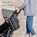 A person walking a stroller with the portable baby nappy changing mat hooked onto the side by its stroller straps.